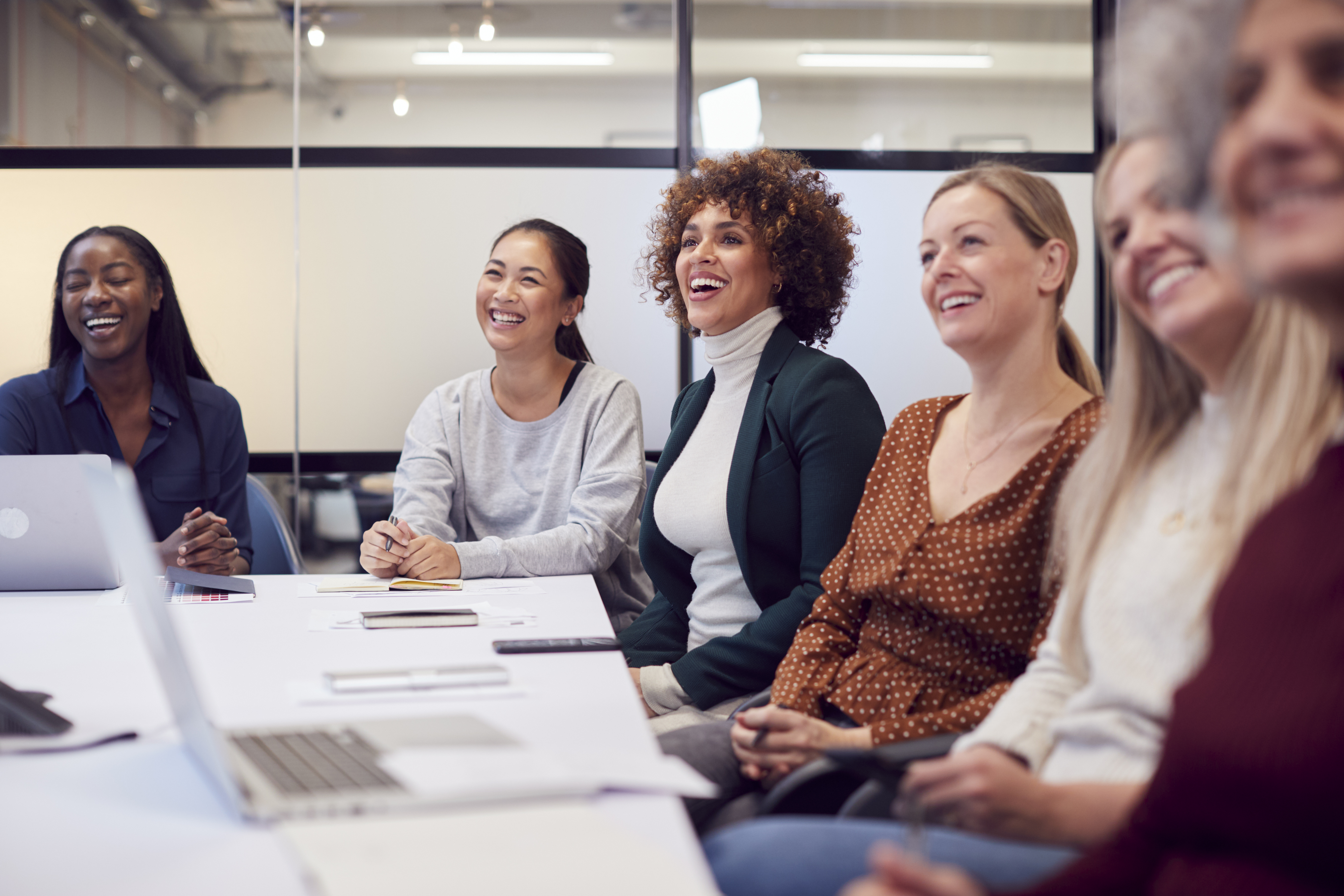 Line Of Businesswomen In Modern Office Listening To Presentation By Colleague